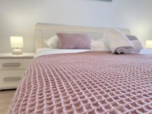 um quarto com uma cama com um edredão rosa em Palit Hills Superior Apartments em Rab