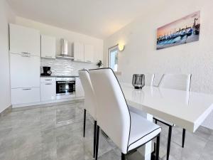- une cuisine blanche avec une table à manger et des chaises blanches dans l'établissement Palit Hills Superior Apartments, à Rab