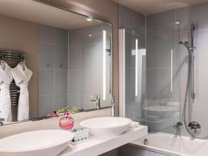 a bathroom with two sinks and a glass shower at Cures Marines Hotel & Spa Trouville - MGallery Collection in Trouville-sur-Mer