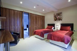 1 Schlafzimmer mit 2 Betten mit roter Bettwäsche und einem Stuhl in der Unterkunft Premier Apartments in Caister-on-Sea