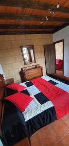 a bedroom with a bed with a red and black quilt at Club JM Lanzarote in Tabayesco