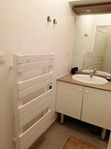 W białej łazience znajduje się umywalka i lustro. w obiekcie Fadil w mieście Valenciennes