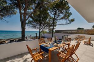 een patio met een tafel en stoelen en de oceaan bij Vera Villa - Brand New Seafront Villa! in Alykes