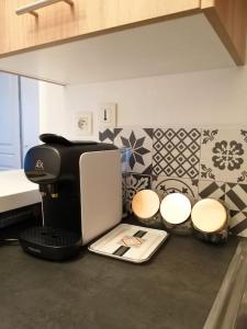 a kitchen counter with a coffee maker and stools at Fadil in Valenciennes