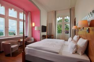 a bedroom with a large bed with pink walls and windows at Hotel Schloss Eckberg in Dresden