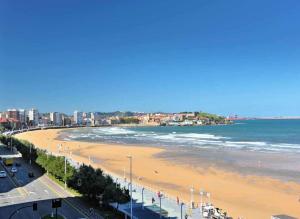 a view of a beach with the ocean and buildings at Lavaderu Apartamento in Gijón