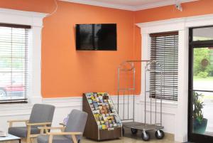フロント・ロイヤルにあるBaymont by Wyndham Front Royal Near Shenandoah National Parkのオレンジ色の壁の客室で、椅子2脚とテーブル1台が備わります。