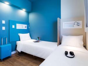 two beds in a room with blue walls at ibis budget Pindamonhangaba in Pindamonhangaba