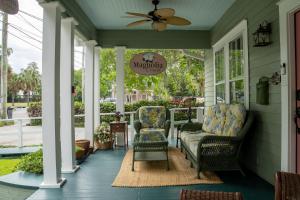 eine Veranda mit 2 Stühlen und einem Deckenventilator in der Unterkunft Magnolia Court Suites in Beaufort