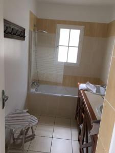 uma casa de banho com uma banheira, um lavatório e uma janela em Gite avec piscine privative em LʼAiguillon-sur-Vie