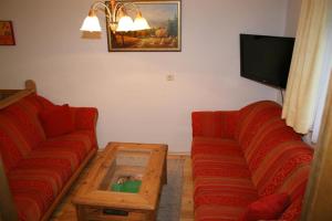 a living room with two red couches and a coffee table at Ferienwohnungen Foidlhof in Hochfilzen