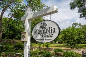 a sign for magnolia court in a garden at Magnolia Court Suites in Beaufort