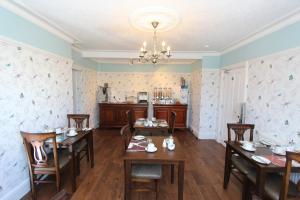 uma sala de jantar com mesas e cadeiras e um lustre em Fern Howe Guest House em Keswick