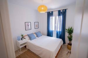 1 dormitorio con cama blanca y cortinas azules en Casa en Tarifa en Primera linea de Playa, en Tarifa
