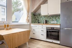 a kitchen with white cabinets and a stove top oven at Apartamentai Čiki puki 2 aukštas in Palanga