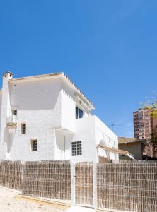 una casa blanca detrás de una valla en Casa MYA con terreno privado y parking compartido - a 800m de Playa Poniente, en Benidorm