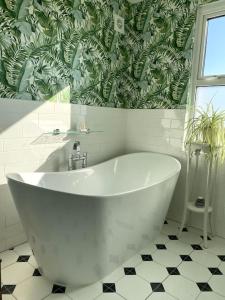 een wit bad in een badkamer met groen behang bij Distinctive Stamford townhouse in Lincolnshire