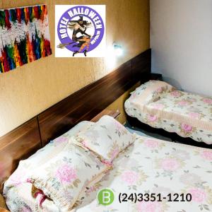 Habitación con 2 camas y un cartel en la pared en Hotel Halloween Inn Penedo, en Penedo