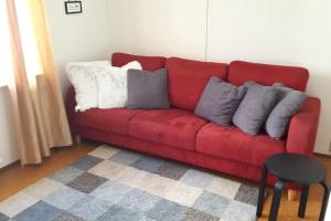 ein rotes Sofa mit Kissen darauf im Wohnzimmer in der Unterkunft Vindsvåning, stenkast från centrum in Pietarsaari