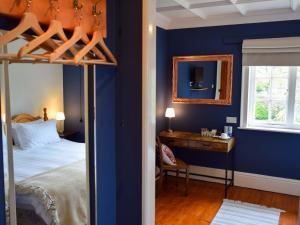 Schlafzimmer mit blauen Wänden, einem Bett und einem Schreibtisch in der Unterkunft Elloe Lodge in Holbeach