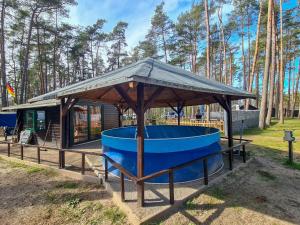 a gazebo with a blue tub in front of a cabin at Urlaub im Bungalow mitten im Wald in Lütow