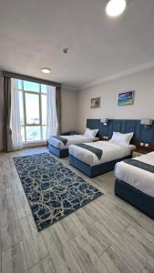 um quarto de hotel com três camas e um tapete em SEAVIEW HOTEL em Umm Lajj