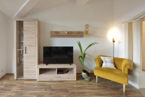 a living room with a television and a yellow chair at Klausner Kunterbunt in Volders