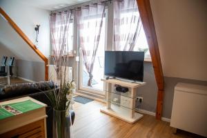 ein Wohnzimmer mit einem TV auf einem Stand vor einem Fenster in der Unterkunft Apartment Auszeit in Isenbüttel