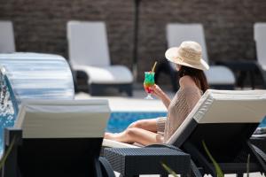 Eine Frau in einem Hut, die mit einem Drink auf einem Stuhl sitzt. in der Unterkunft Villa Sara in Nikiti