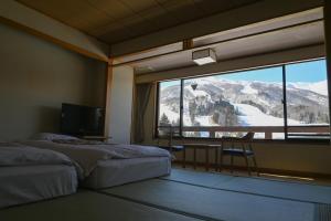 a bedroom with a large window with a mountain view at Hotel Goryukan in Hakuba