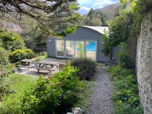 un pequeño cobertizo con una mesa de picnic y un banco en The Elmfield, 8 Bed Villa with heated indoor Swimming Pool and Cocktail Bar, en Ilfracombe