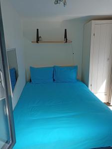 ein blaues Bett mit blauen Kissen im Schlafzimmer in der Unterkunft Little Beach Place in Zandvoort