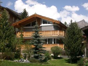 ein Haus in den Bergen mit einem Baum in der Unterkunft Chalet Sunshine in Saas-Fee