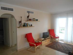 ミハス・コスタにあるApartment in Las Palmeras de Calahondaのリビングルーム(赤い椅子2脚、テレビ付)