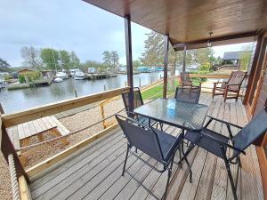 a table and chairs on a deck with a view of a river at River Rest - Norfolk Broads in Brundall