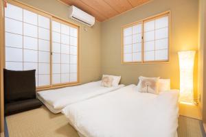 two beds in a room with two windows at HANAMIKAKU-shinjuku/akihabara/asakusa/ginza/tokyo/narita/haneta Japanese House 100㎡ in Tokyo