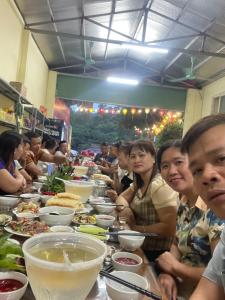 un grupo de personas sentadas en una mesa larga en Khách Sạn Hà Phương en Ninh Binh