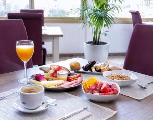 a table with breakfast foods and a glass of orange juice at Hotel Ankaa - Adults Only in Porto Cristo