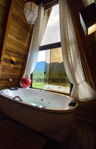 a bath tub in a room with a large window at Vista dos Canyons in Praia Grande