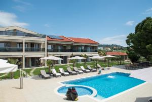 einem Pool mit Stühlen und Sonnenschirmen vor einem Gebäude in der Unterkunft Villa Sara in Nikiti