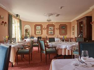 uma sala de jantar com mesas e cadeiras com toalhas de mesa brancas em Corse Lawn House Hotel em Corse