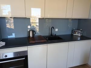 kuchnia z białymi szafkami i zlewem w obiekcie Kapitańska Apartament w mieście Gdynia