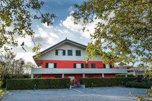 un bâtiment rouge et blanc avec des buissons devant lui dans l'établissement Lepini Suites, à Patrica