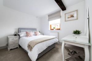 a white bedroom with a bed and a desk at Hideaway Cottage Bewdley with parking near the River Severn in Bewdley
