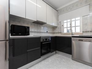 a kitchen with black and white cabinets and a microwave at Akisol Albufeira Water in Albufeira