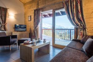 een woonkamer met een bank en een groot raam bij CGH Résidences & Spas Chalet Les Marmottons in La Rosière