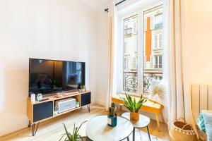 ein Wohnzimmer mit einem großen TV und einem Fenster in der Unterkunft GuestReady - Lovely urban retreat in the 17th Arr. in Paris