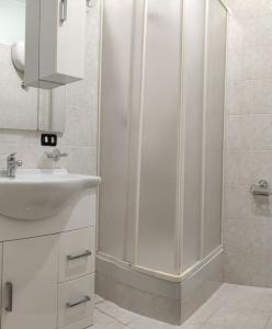 een witte badkamer met een douche en een wastafel bij Casa vacanze in famiglia in San Leucio del Sannio