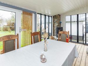 Holiday home Hjørring XXXV في يورينغ: غرفة طعام مع طاولة بيضاء ونوافذ