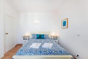a white bedroom with a bed with blue sheets and blue pillows at Casa do Coral - Praia da Luz in Luz